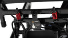 Close-up of a black metal frame component with two red coil springs and a hanging black tag that reads WARNING with a rabbit icon and folding instruction.