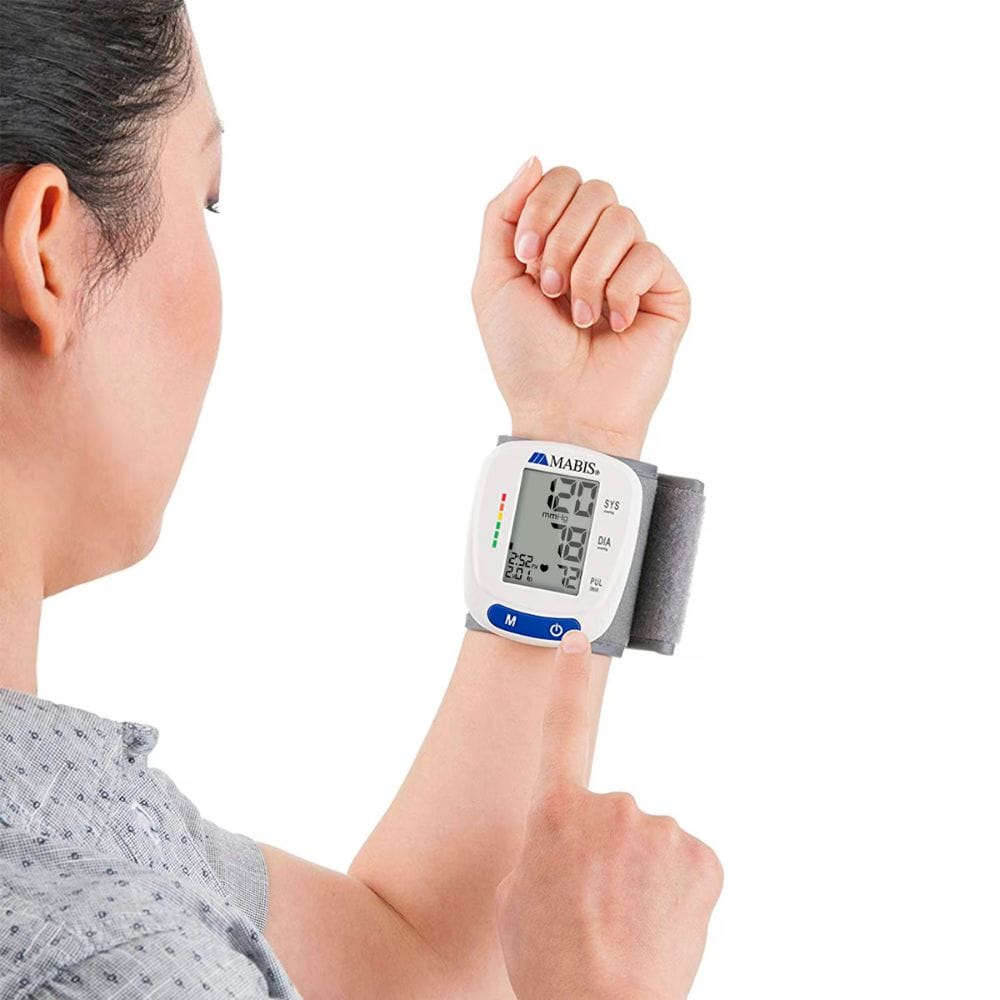 Person using a digital blood pressure monitor on their wrist with a white background