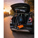 Car trunk with a tire inflator and toolbox during sunset.