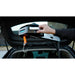 Person using a portable car jack to lift a car with an open trunk.