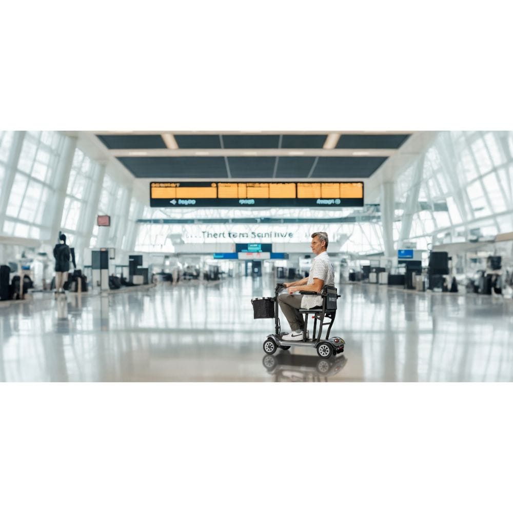 Person using a mobility scooter in an airport terminal with a large digital display board in the background.