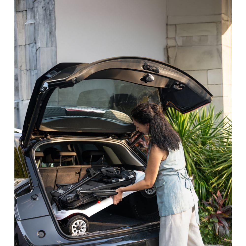 Woman loading a suitcase into the trunk of a car outdoors.