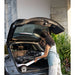 Woman loading a suitcase into the trunk of a car outdoors.