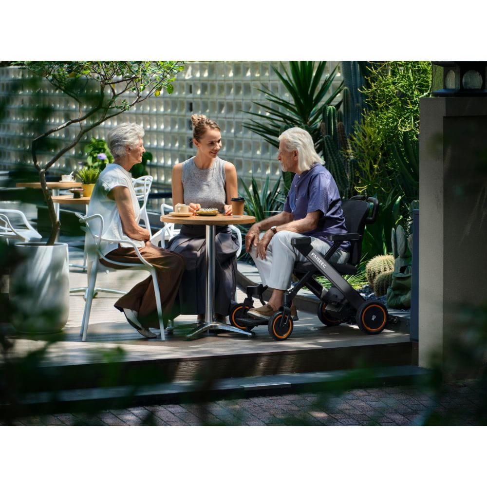 Two people sitting at a table with a baby in a stroller on a patio.