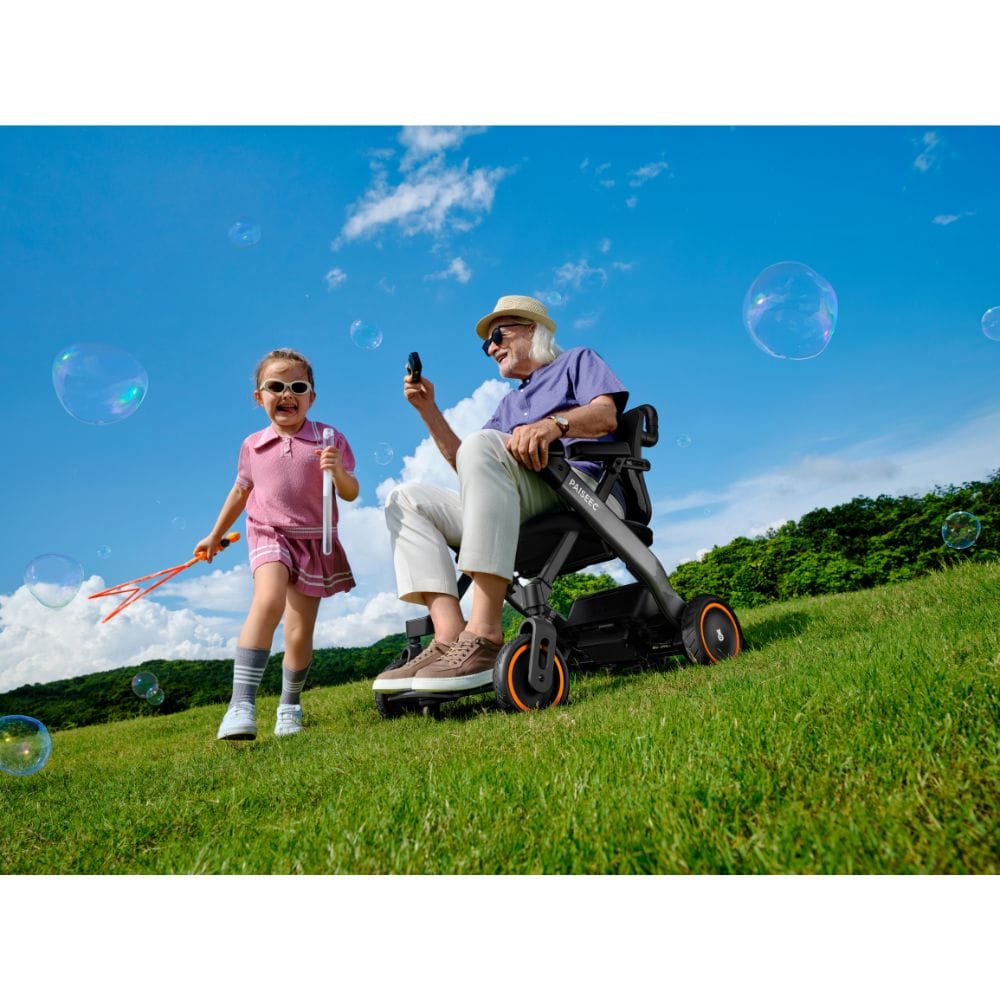 Man in a wheelchair and young girl playing with bubbles outdoors on a sunny day.