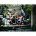 Two people sitting at a table with a baby in a stroller on a patio.