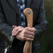 Person holding a wooden paddle with a brand logo, wearing a dark jacket.