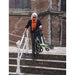 Person using a rollator on steps in front of a brick building