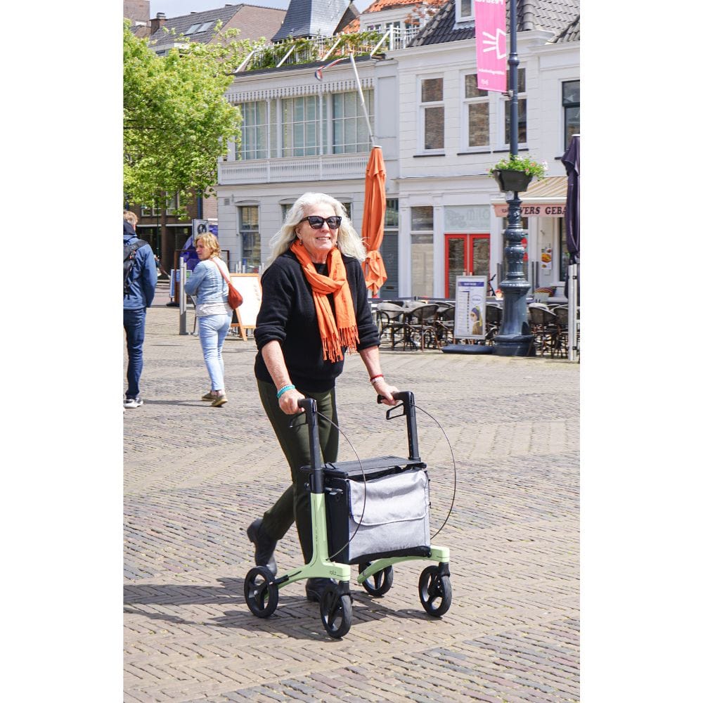 Woman pushing a green rolling stroller in an urban setting