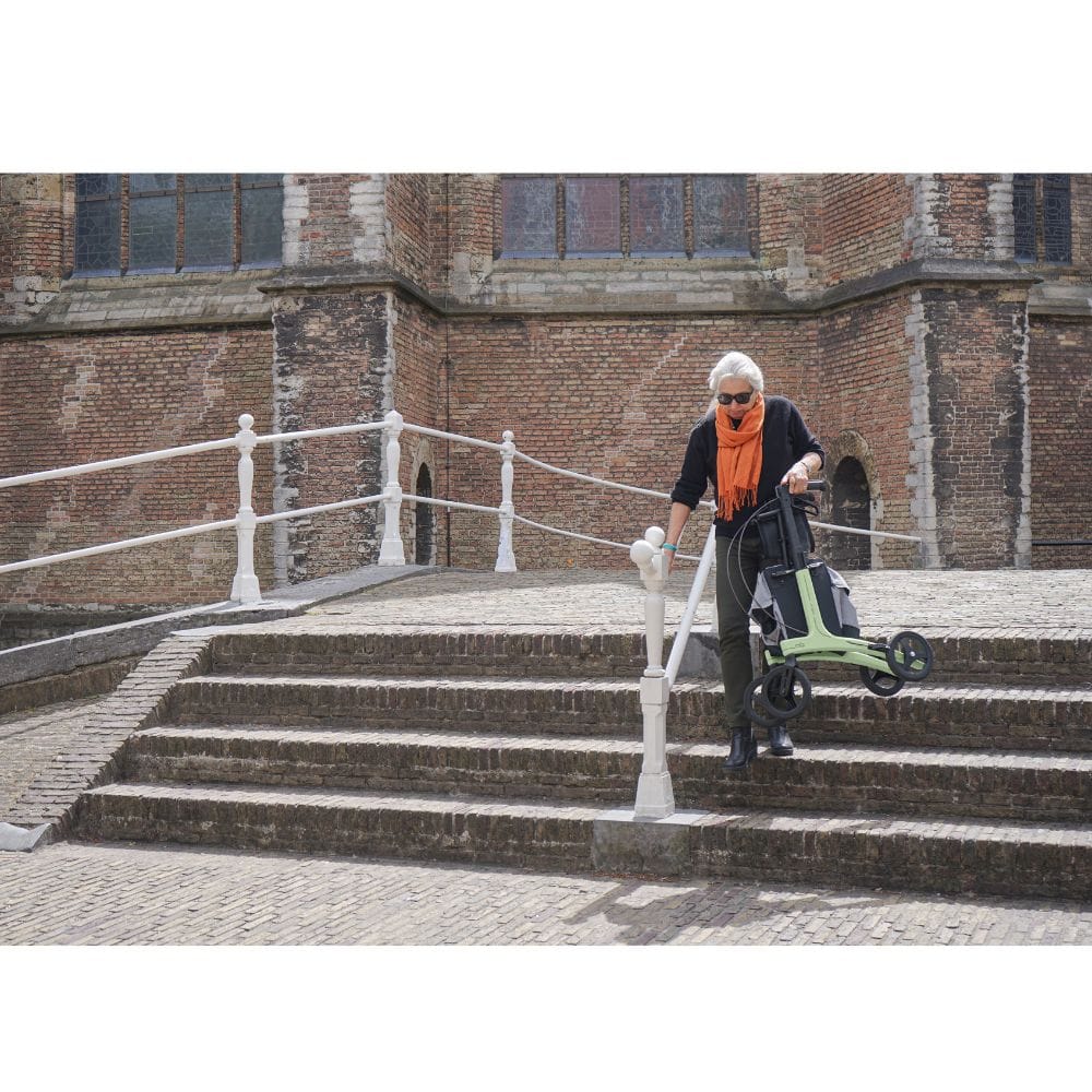 Person pushing a stroller up a set of stairs in front of a brick building.