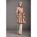 Woman wearing a beige trench coat and holding a cane against a gray background