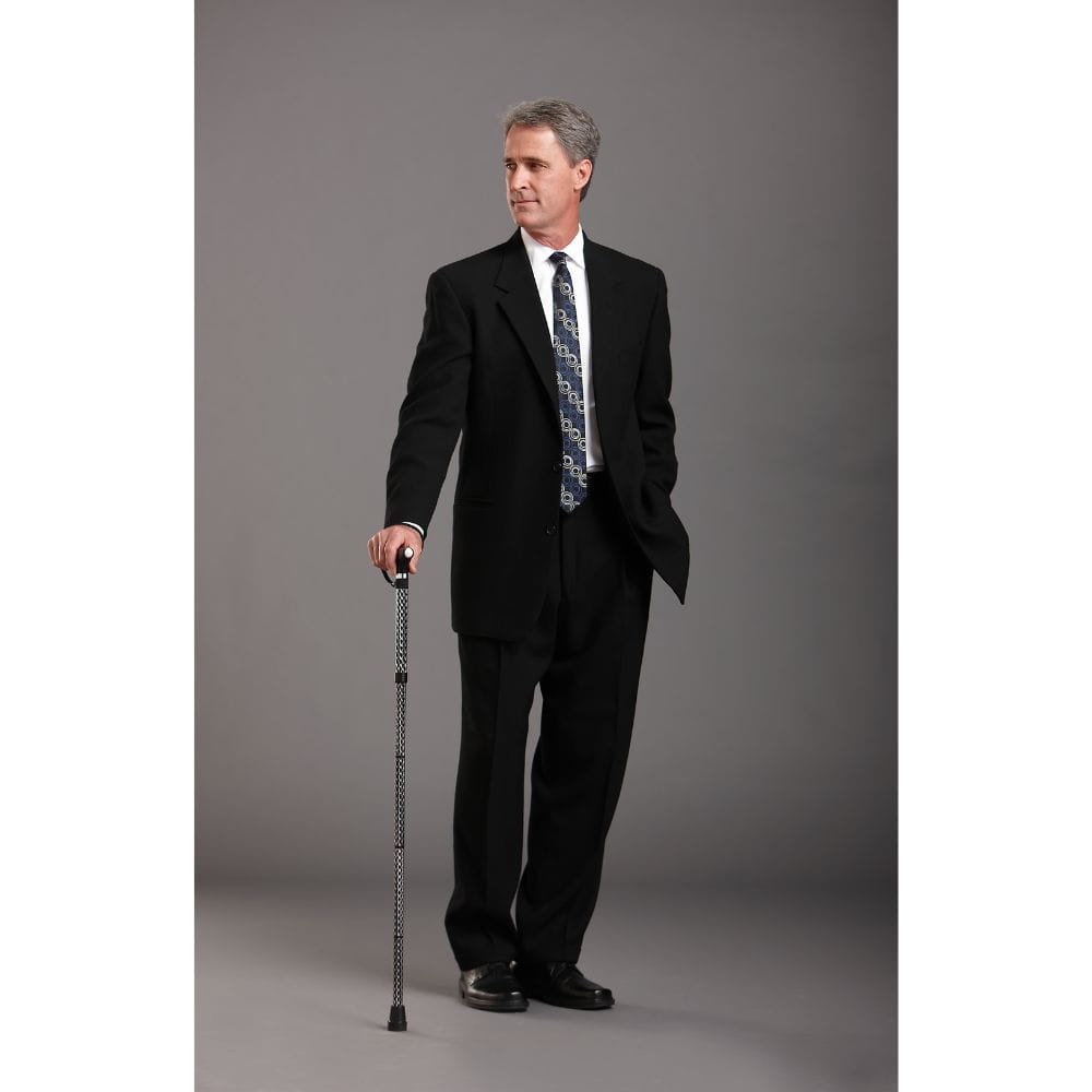Man in a black suit holding a cane against a gray background