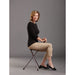 Woman sitting on a small stool against a gray background