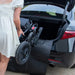 Person loading a black wheelchair into the trunk of a car