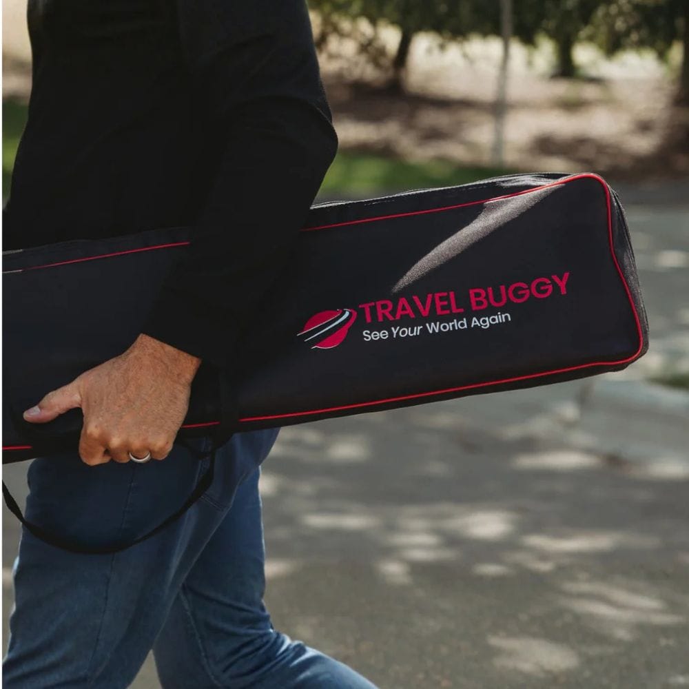 Person holding a black travel buggy with 'Travel Ruggy' branding outdoors.
