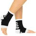 Black and white compression ankle sleeves on a person's legs against a white background
