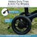 Close-up of a wheel with anti-tip wheels and heavy-duty tires on a grassy background.