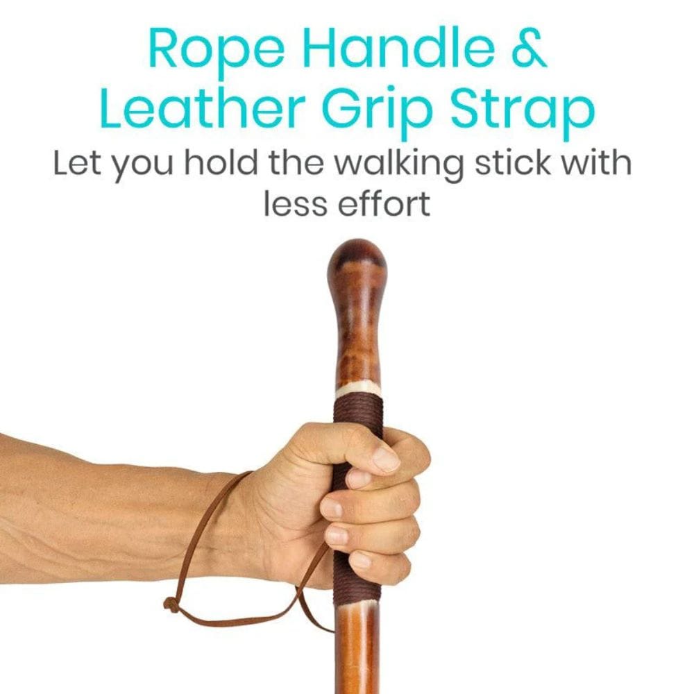 Hand holding a walking stick with a rope handle and leather grip strap on a white background.