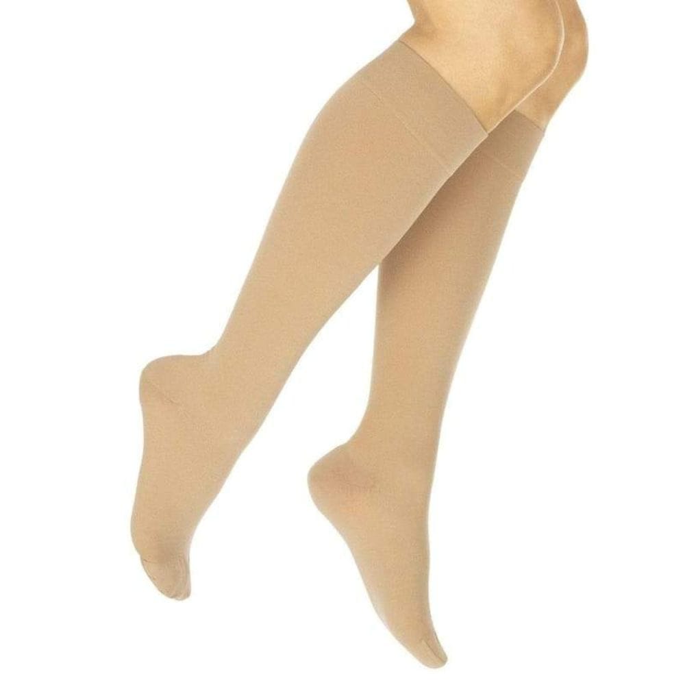 Beige compression stockings on a mannequin leg against a white background