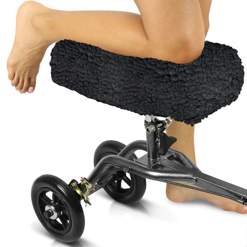 Person using a knee scooter with a black cushioned seat on a white background