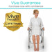Woman in a white robe sitting on a shower chair with Vive Health Lifetime Guarantee badge.