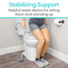 Person using a stabilizing support device while sitting on a toilet in a bathroom.