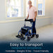 Man using a foldable walker in a room with large windows.
