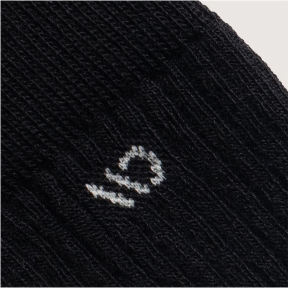 Close-up of a black sock with a white logo on a light gray background