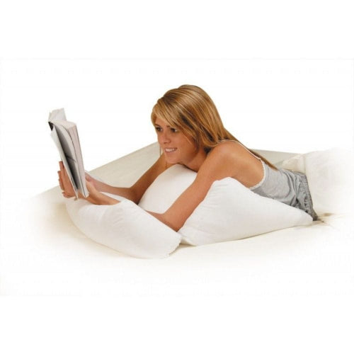 A woman lying on a bed reading a magazine, supported by a white contoured pillow.