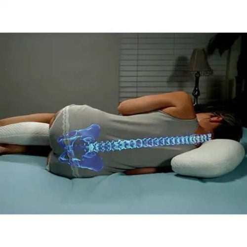 A person lying on a bed in a bedroom, shown from the back, wearing a gray tank top and using a white pillow. A blue anatomical spine overlay highlights the back and lower back area.
